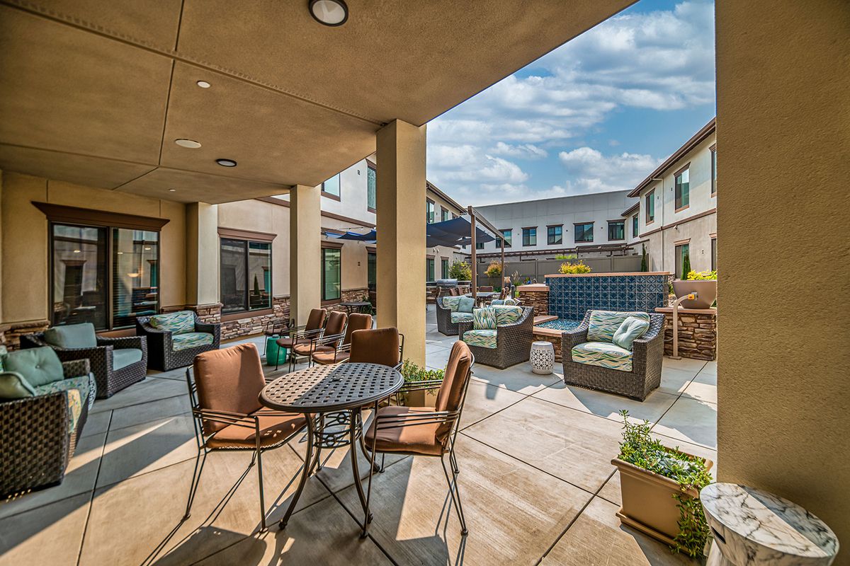 A spacious outdoor patio with comfortable seating and tables, perfect for relaxation on a sunny day.
