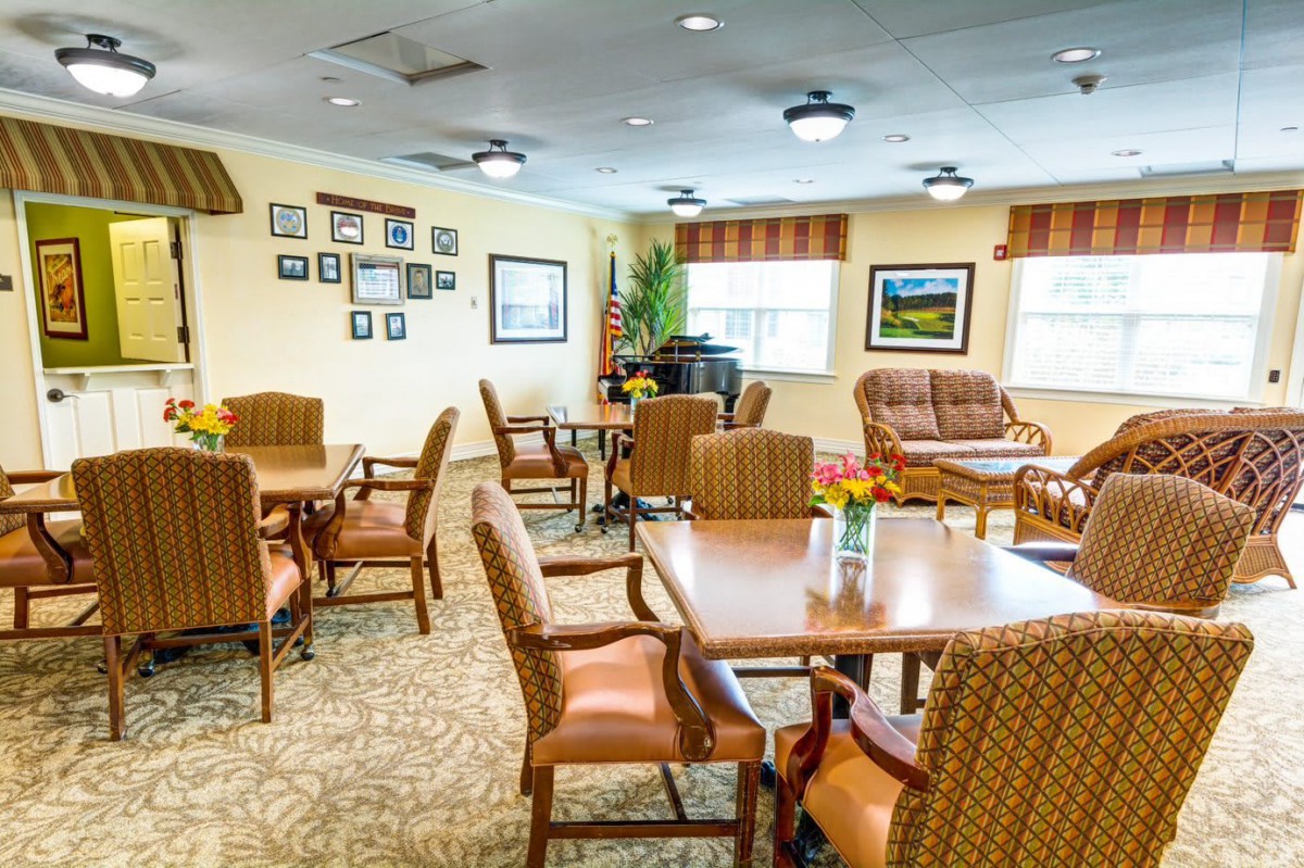 A well-furnished dining and lounge area with tables, chairs, and a piano, offering a cozy setting.
