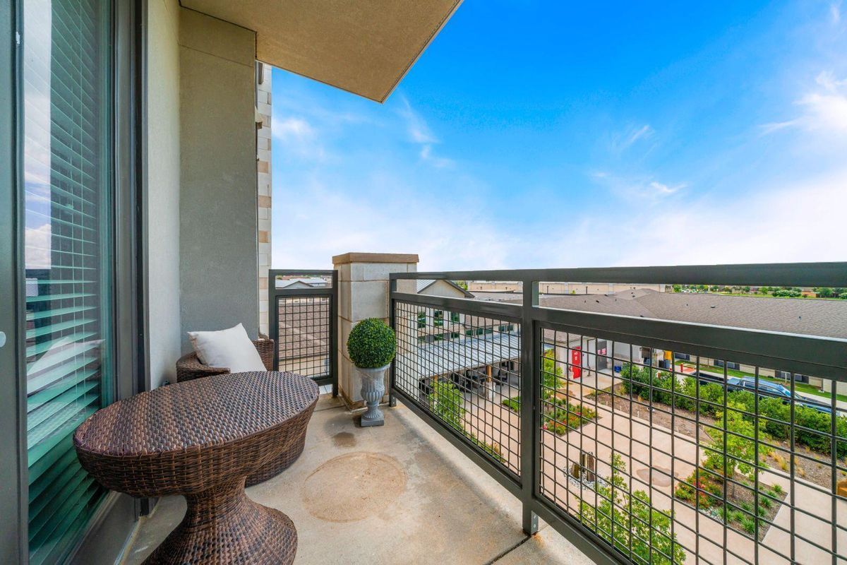 A cozy balcony with seating and a view of the surrounding area under a clear blue sky.
