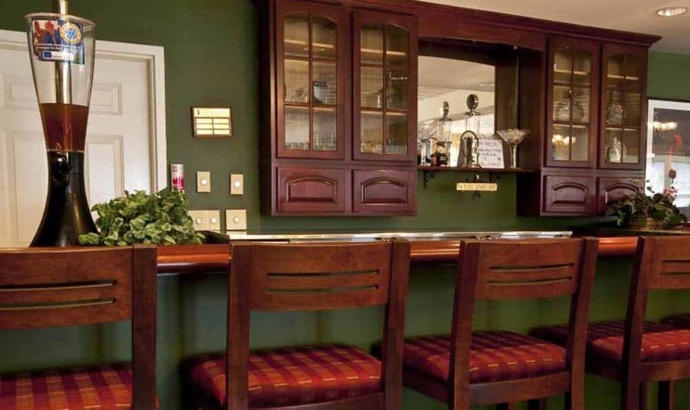 A cozy kitchen space featuring wooden cabinets and bar stools against a green wall.