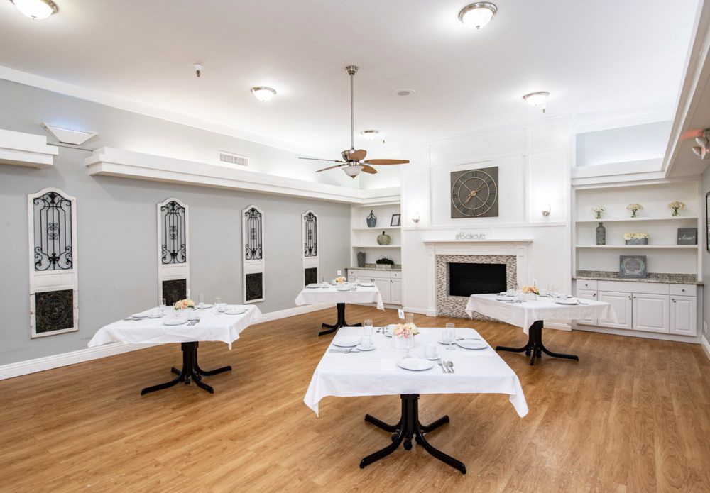An elegantly decorated dining room with tables set with white tablecloths and a fireplace.
