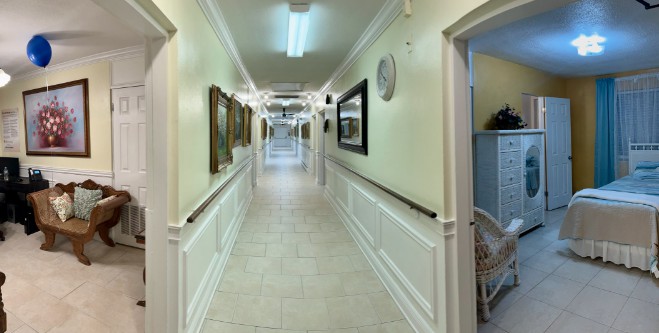 A well-lit hallway with paintings and a clock on the walls.