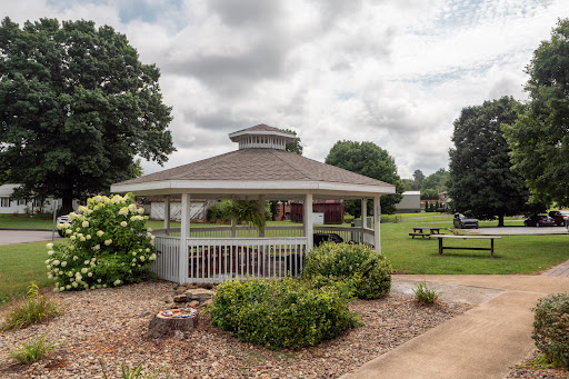 A charming gazebo surrounded by lush greenery in a serene park setting.