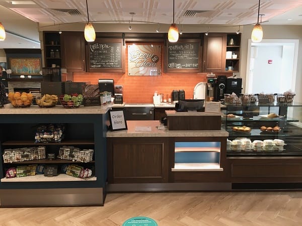 A cozy coffee shop with a counter displaying pastries and a menu board in the background.