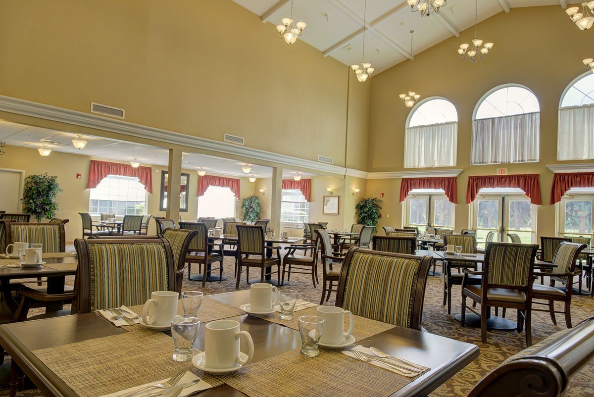 A spacious dining area with multiple tables and chairs, elegantly decorated with large windows and modern lighting.