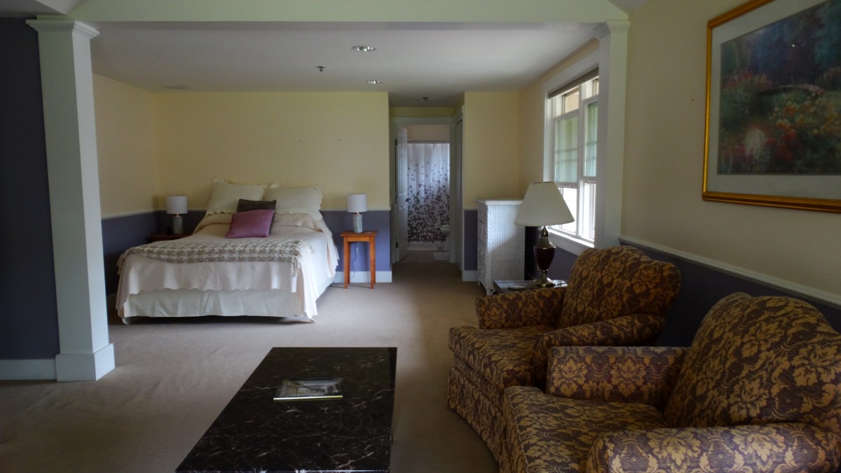 A comfortable bedroom with a bed, seating area, and natural light.