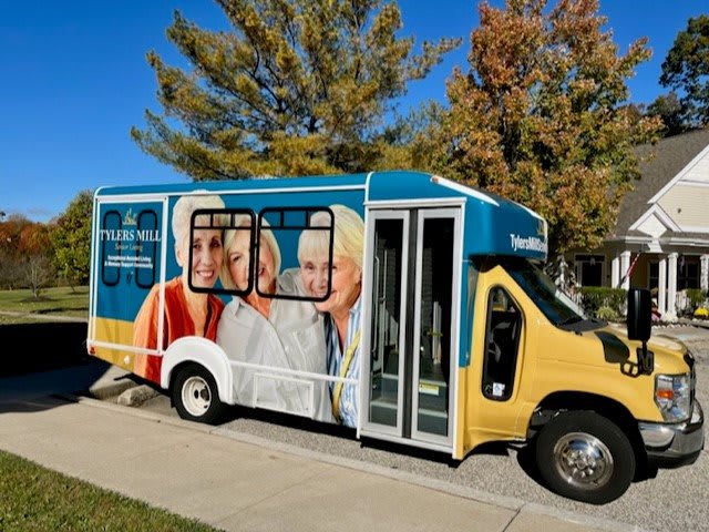 A brightly colored bus with an advertisement featuring seniors, parked on a sunny day.