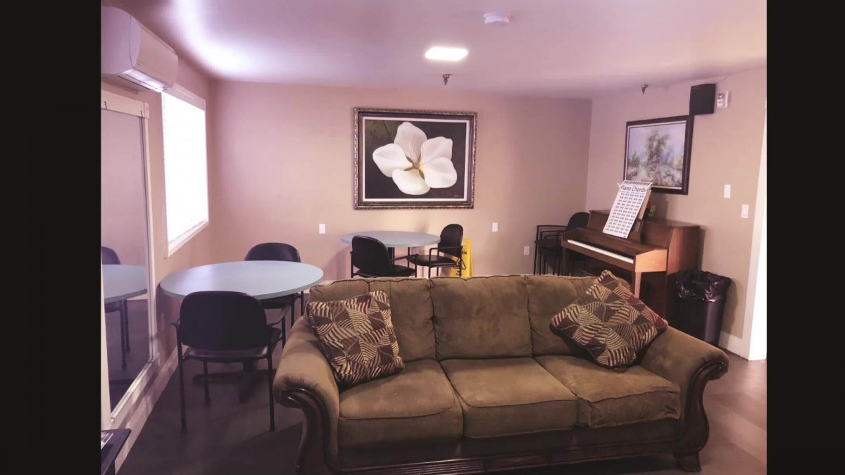 A cozy living room with a sofa, piano, and artwork on the wall.
