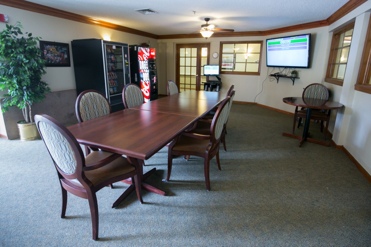 A spacious conference room featuring a long meeting table, comfortable chairs, and vending machines.