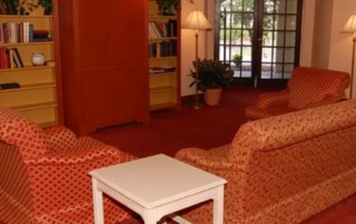A cozy living room with armchairs, a small table, and a bookshelf.