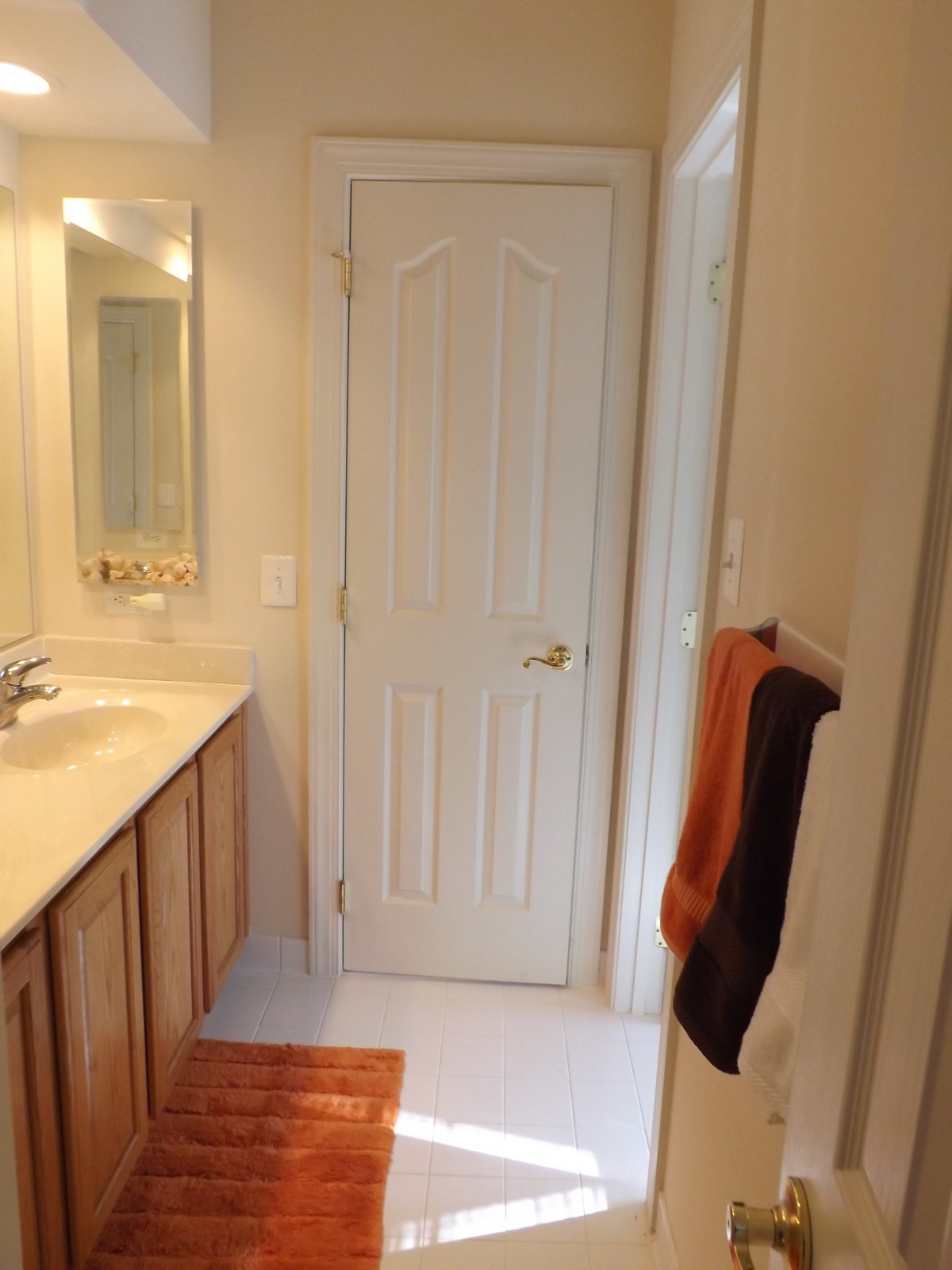 A bathroom interior featuring a sink, mirror, and towels hanging on the wall.