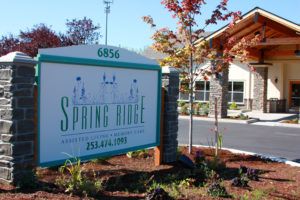 A sign for Spring Ridge in front of a building with landscaped surroundings.