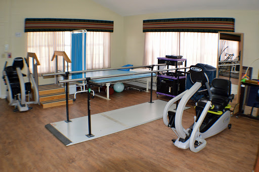 A well-equipped physical therapy room featuring a ballet bar, exercise mats, and various fitness equipment.