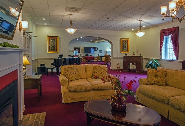 A cozy living room with elegant decor, featuring plush sofas, a piano, and warm lighting.