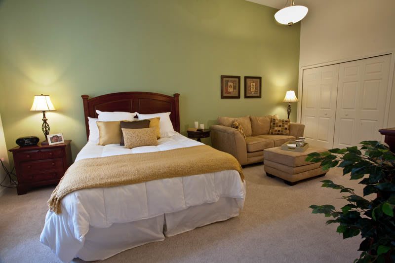A cozy bedroom with a bed and sofa, complemented by warm lighting and decor.