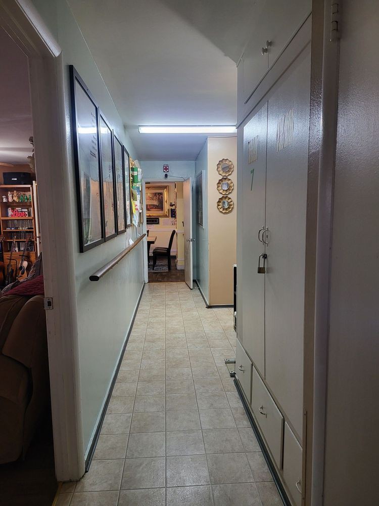 A well-lit hallway in a home with wall art and tiled flooring.