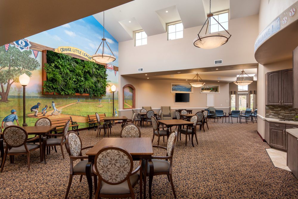 A well-lit dining area with a mural, featuring round tables and upholstered chairs.
