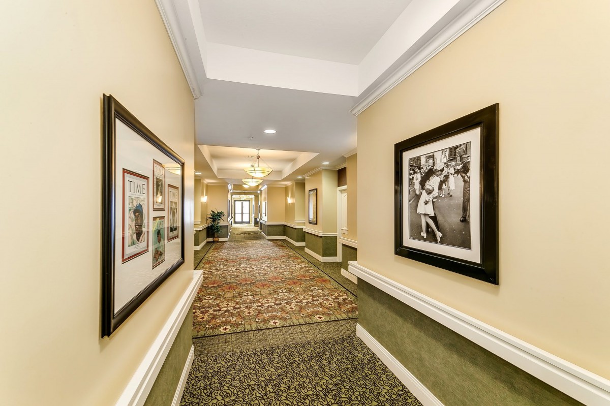 A well-lit hotel hallway adorned with framed artwork and a patterned carpet.