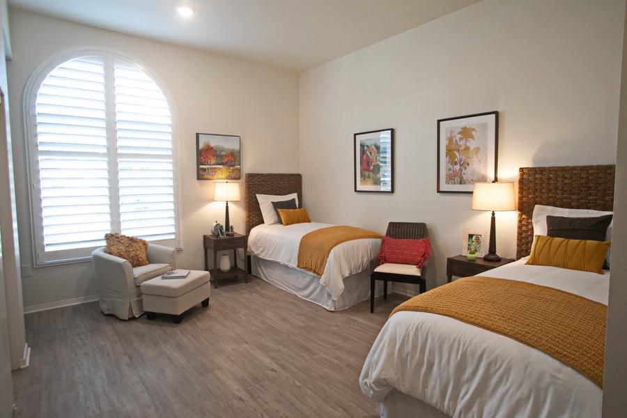 A modern bedroom with two beds, featuring warm lighting and stylish decor.