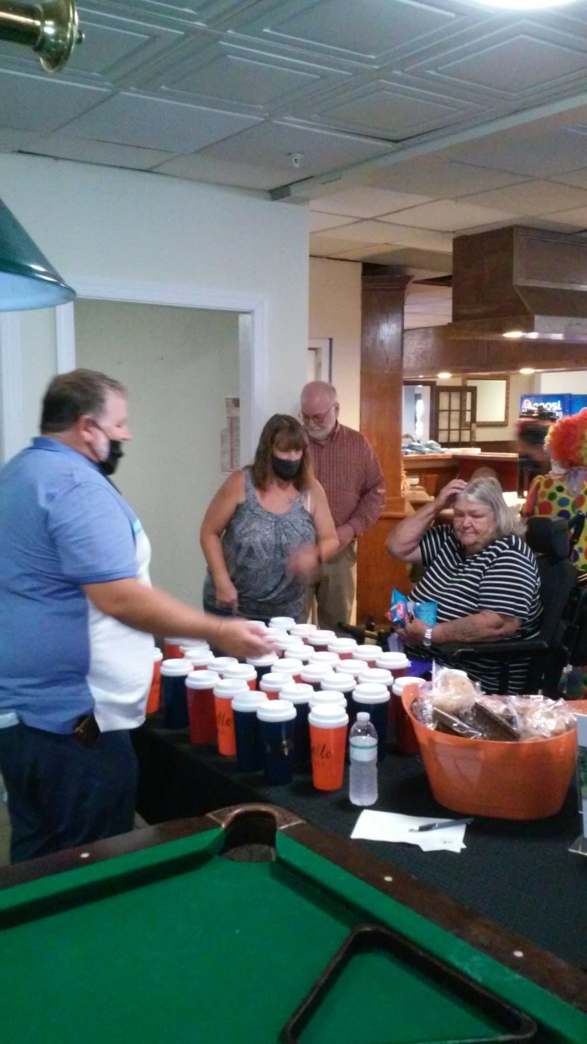 A group of people gathered indoors at a table displaying food and drinks.
