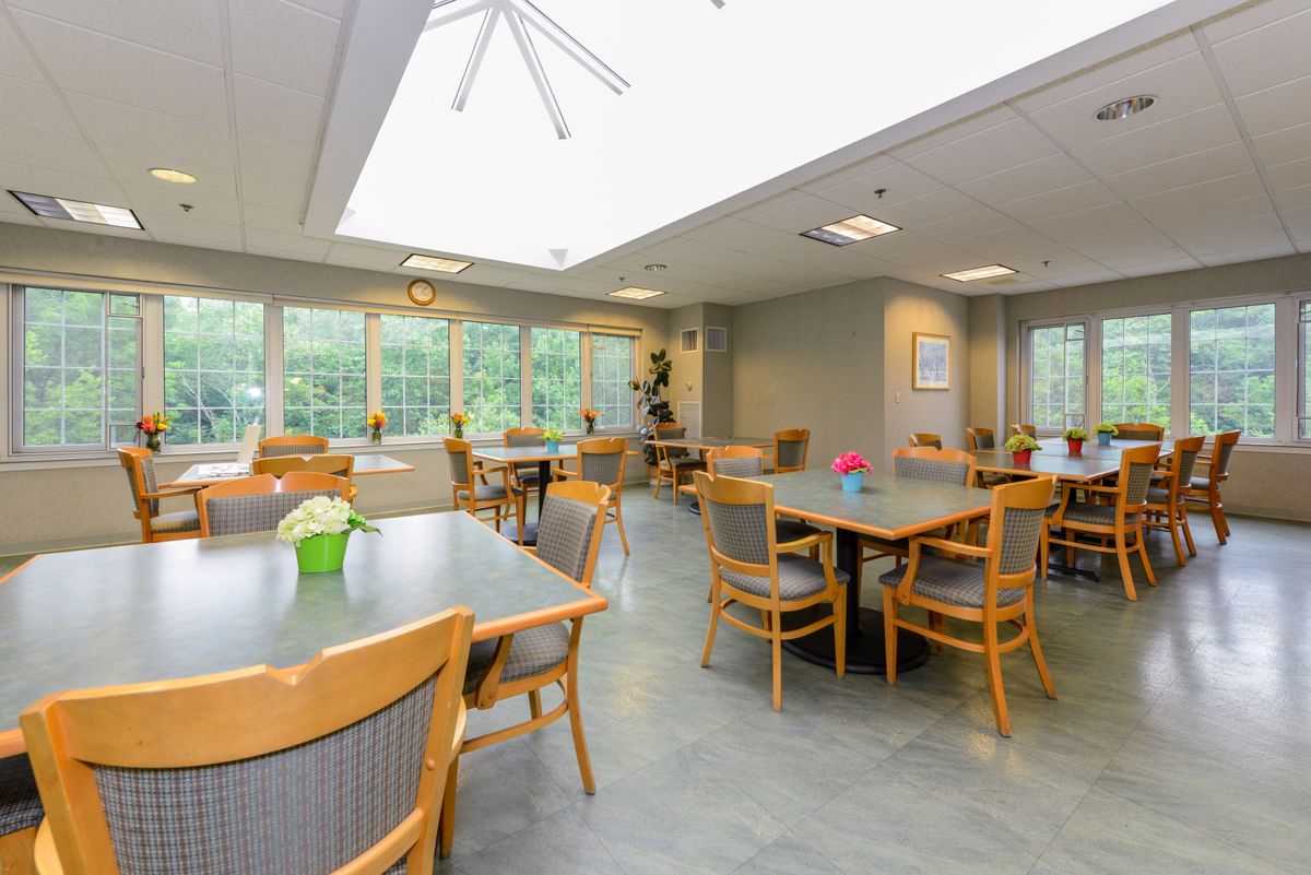 A bright and spacious dining area with multiple tables and chairs, featuring large windows that allow natural light to fill the room.