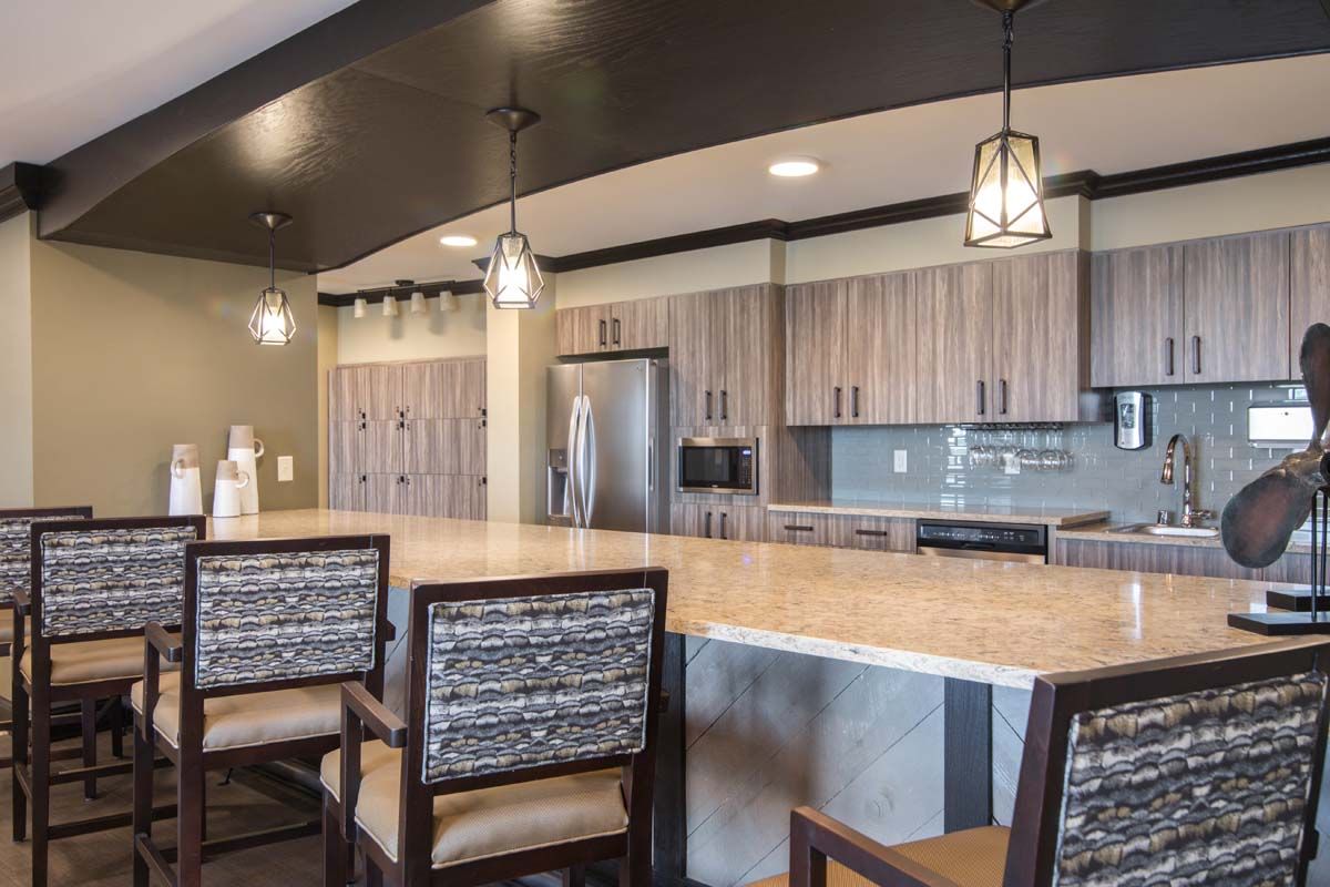 A modern kitchen with wooden cabinets, an island with bar stools, and stylish lighting fixtures.