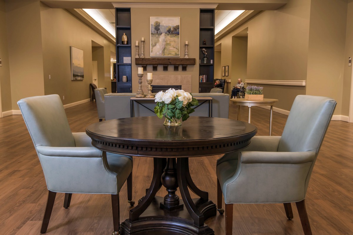A cozy living room with elegant furniture and a central table adorned with flowers.