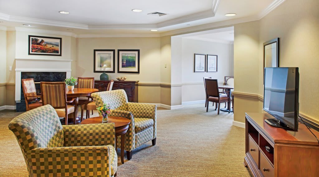 A cozy living room area featuring comfortable chairs, tables, and warm lighting.