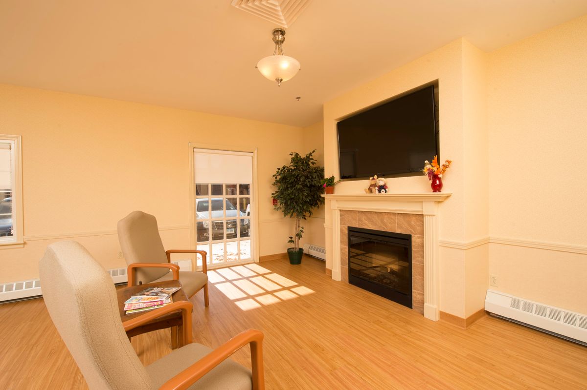 A cozy living room with a fireplace, television, and armchairs.