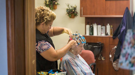 A hair stylist applies color foils to a client's hair in a cozy salon setting.