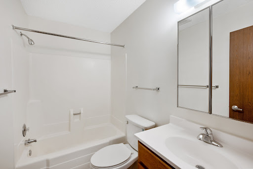 A clean and minimalist bathroom featuring a bathtub, toilet, and sink.