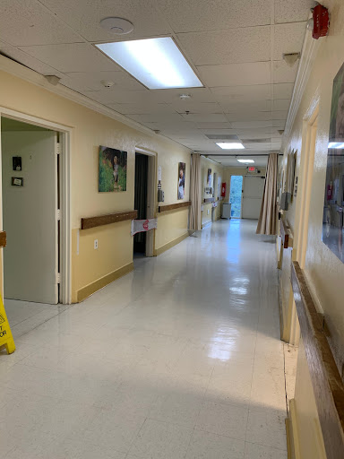 A clean and bright hospital hallway with doors and artwork along the walls.