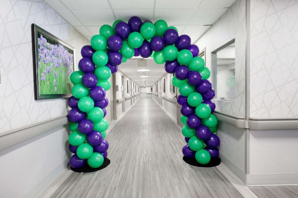A colorful balloon arch decorates a hallway, creating a festive atmosphere.