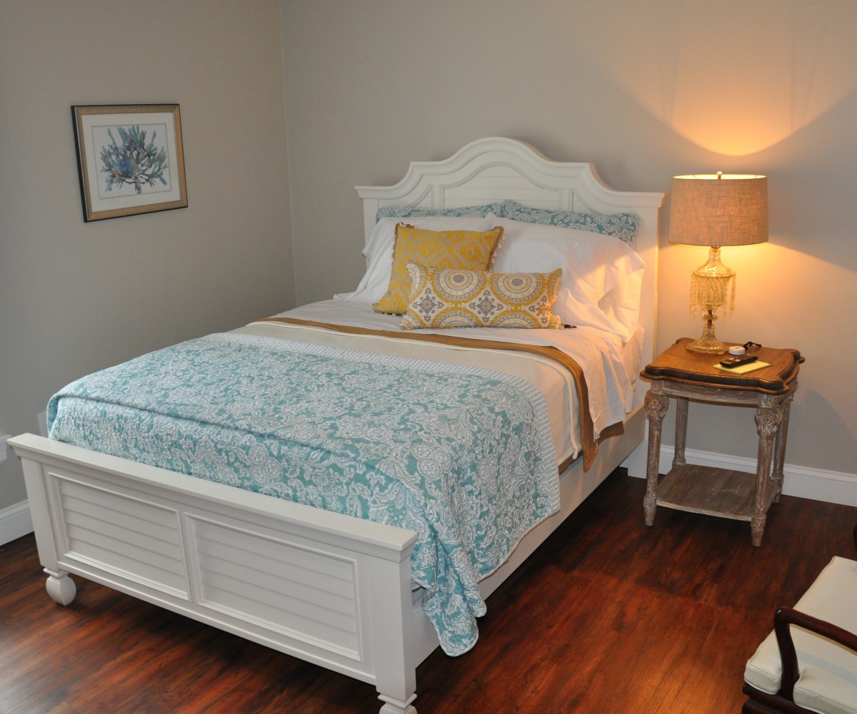 A cozy bedroom featuring a neatly made bed with blue and white bedding, complemented by a wooden nightstand and a warm lamp.