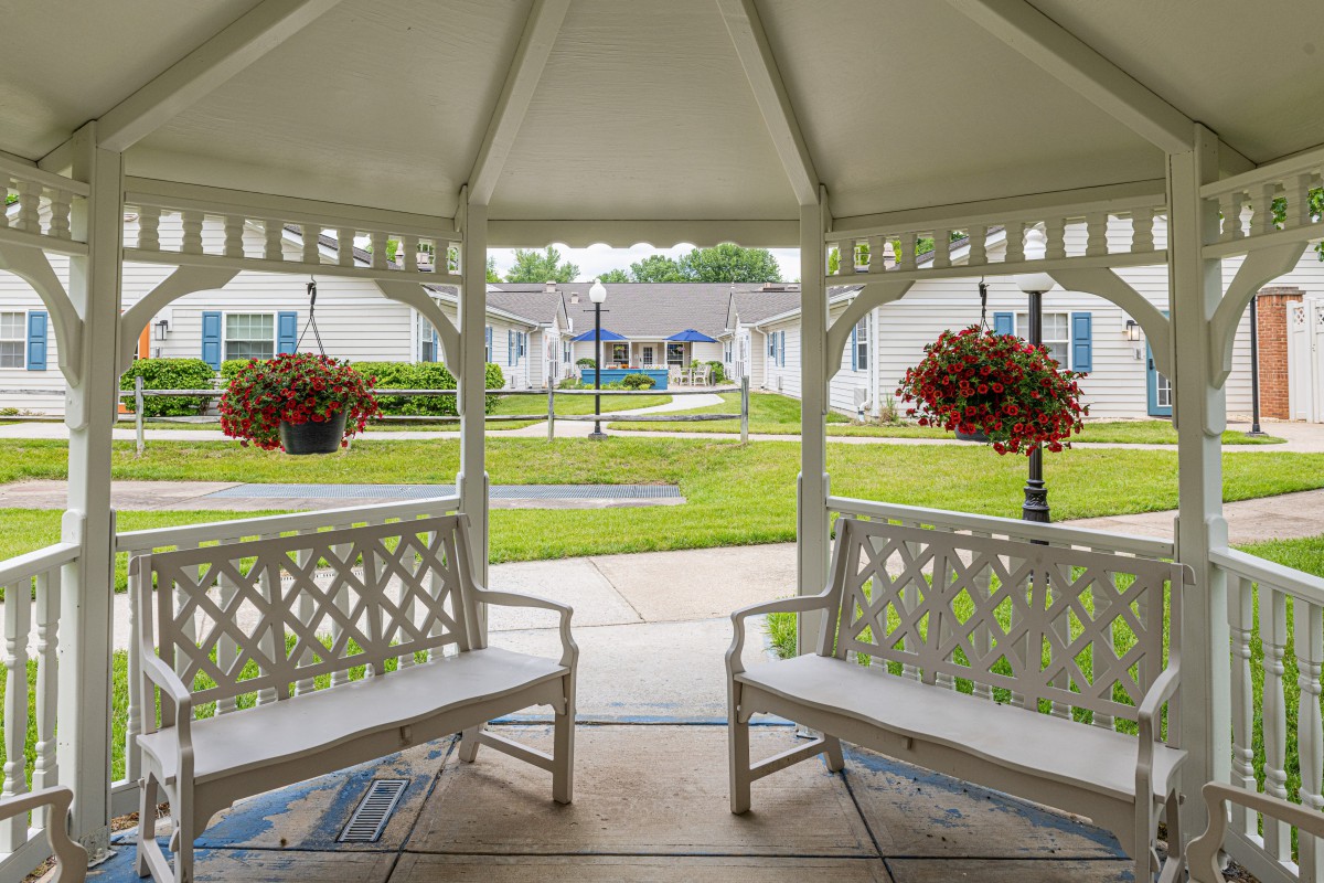 View from a gazebo overlooking a garden with benches and flower arrangements.