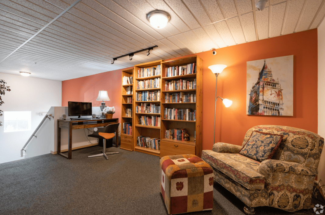 A cozy living room with a bookshelf, desk, and comfortable seating area.