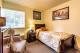 A cozy bedroom with a bed, chair, and wall art.
