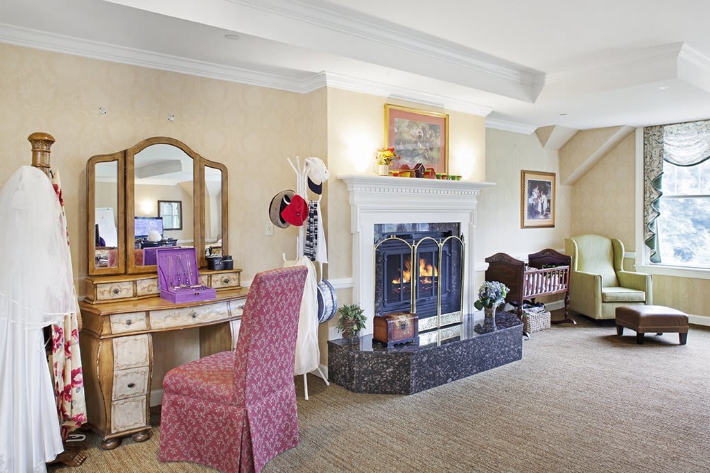 A cozy living room featuring a traditional-style fireplace and a vanity table with an upholstered chair.