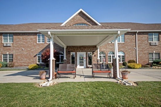 A brick building with a covered entrance and landscaped surroundings.