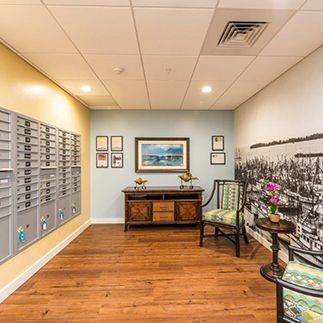 A cozy mailroom with decorative elements, including a wooden table, artwork on the walls, and seating arrangements.