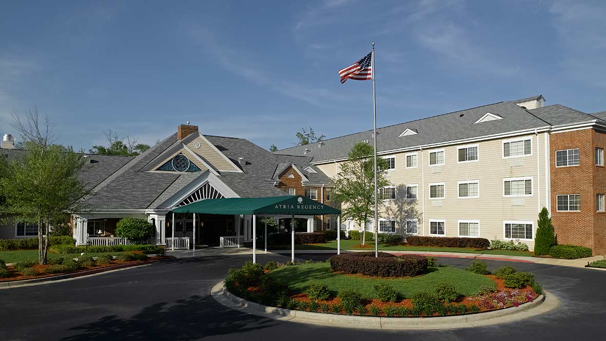 A hotel building with a flag flying above the entrance and well-maintained landscaping.