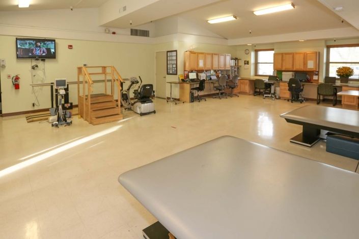 A spacious rehabilitation room equipped with various exercise machines and therapy equipment.