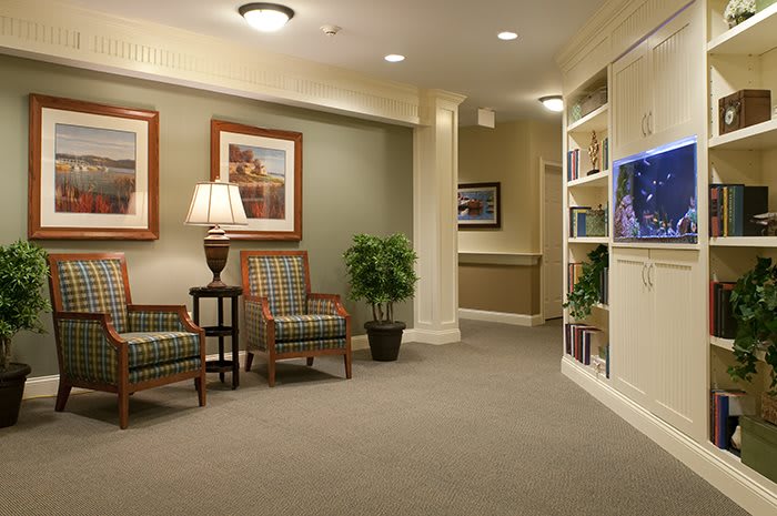 A cozy lobby area featuring comfortable chairs, a lamp, a potted plant, and decorative artwork.