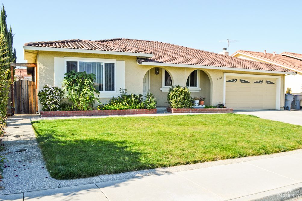 A suburban single-story house with a well-maintained lawn and garden.