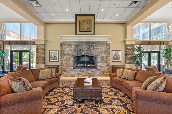 A cozy living room with a central stone fireplace, flanked by two comfortable sofas and a decorative carpet.