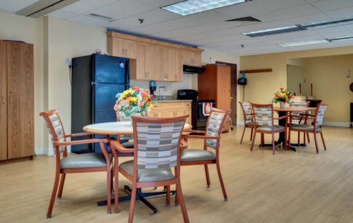 A well-lit kitchenette with tables and chairs, adorned with flower arrangements.