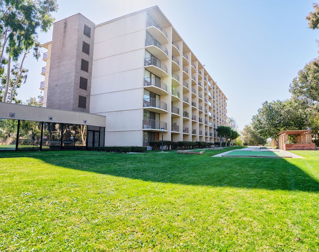 A residential apartment building with balconies and a well-kept lawn in front.