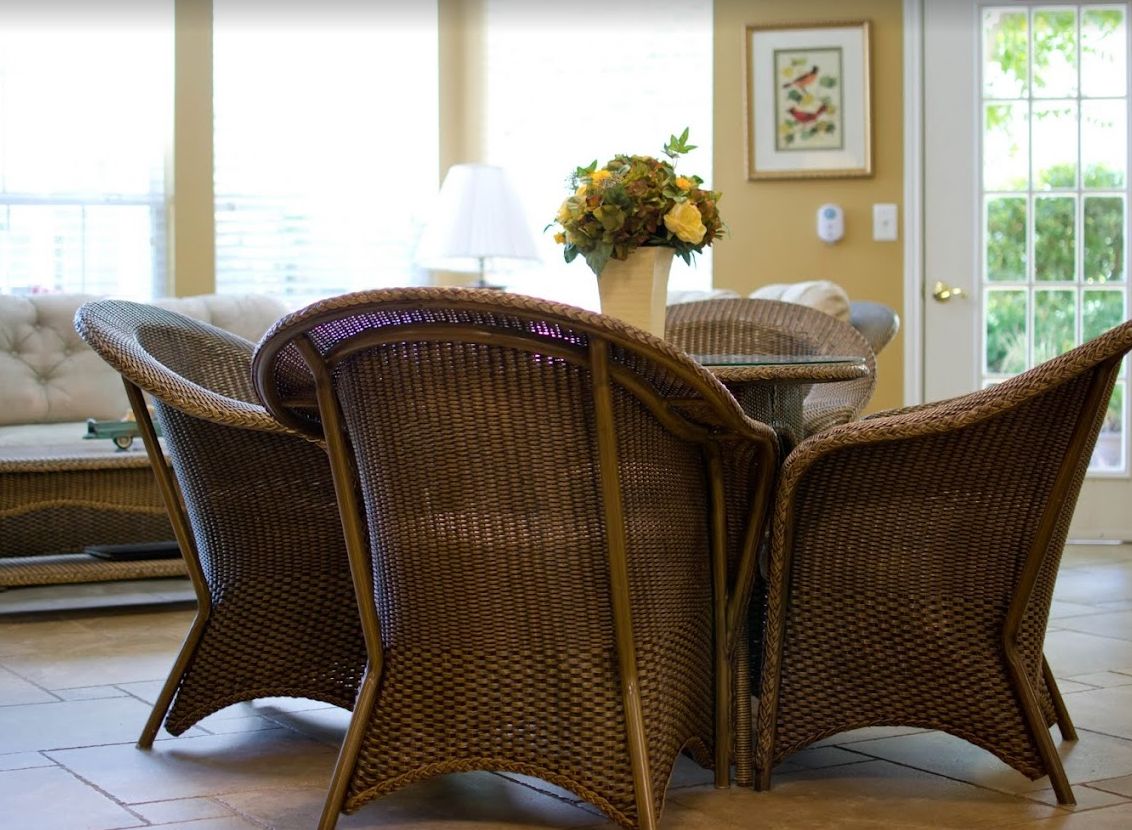 A cozy indoor setting with wicker chairs and a table adorned with a floral centerpiece.