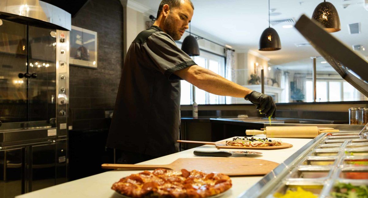 A chef preparing pizzas in a modern kitchen.