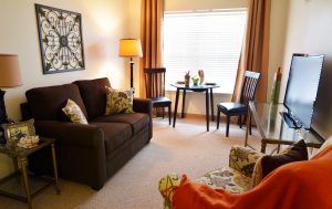 A cozy living room with a sofa, chairs, and a coffee table by the window.